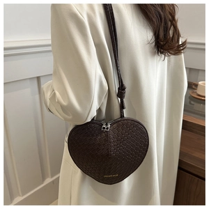 Detail of dark brown heart-shaped woven bag with knot strap and double zipper accents