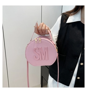 Pink round leather handbag featuring SM embossed letters and stylish gold double zippers