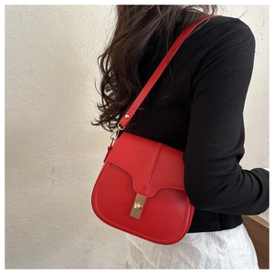 Detailed close-up of a red leather saddle bag with golden buckle on a model