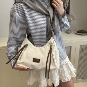 Cream white Hobo bag with brown straps and double zippers in a cozy home setting