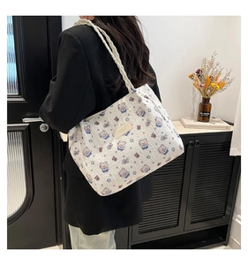 Detail of white quilted tote bag with bear print and woven shoulder strap on a model