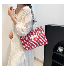 Detail of red and white striped tote bag with cherry prints and woven shoulder strap
