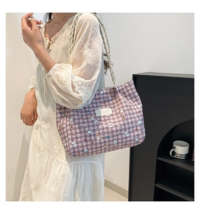 Detail of purple plaid canvas tote bag featuring cute cartoon dogs and white logo label
