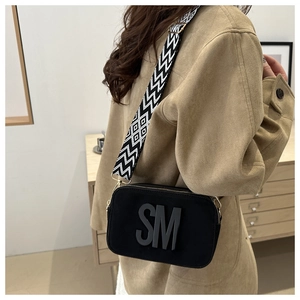 Detail of black camera bag with 3D SM logo and wide geometric woven shoulder strap