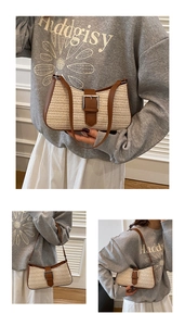 Detail of woven straw crossbody bag with brown leather trim and metal buckle closure