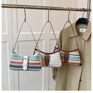 Three straw baguette bags with leather straps hanging on a wooden rack background