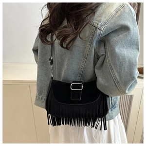 Détail d'un sac bandoulière noir en suédine avec boucles argentées et longues franges