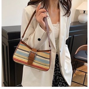 Detail of colorful woven straw underarm bag with brown faux leather trim and buckle