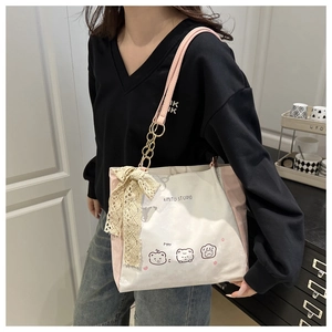Detail of printed tote bag featuring a pink leather chain strap and lace bow accent