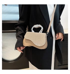 Close-up of champagne gold rhinestone handbag with sleek metal handle on black blazer