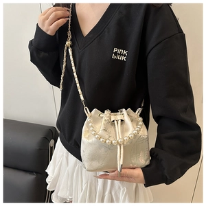 Detail of silk bucket bag with floral embroidery, pearl handle and gold chain strap