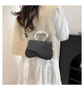 Détail d'un mini sac à paillettes noires avec base asymétrique et poignée métallique