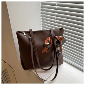 Détail d'un sac cabas en similicuir marron foncé avec foulard en soie sur un rebord