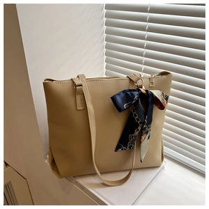 Détail du sac cabas en cuir beige avec foulard en soie décoratif près de la fenêtre