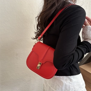 Borsa a sella rossa minimalista con fibbia in metallo dorato indossata da una modella