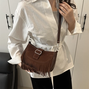 Sac bandoulière vintage marron foncé en daim avec franges porté par un mannequin