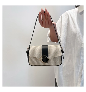 Détail du sac bandoulière en paille avec bordure en cuir noir et boucle en métal doré