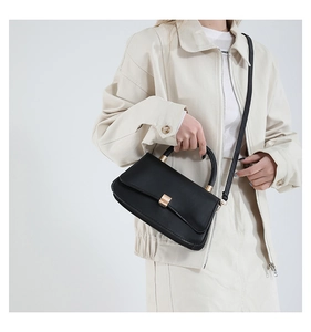 Dettaglio di una borsa a mano nera minimalista con fibbia dorata indossata da modella