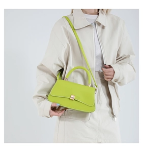 Dettaglio della borsa a tracolla verde neon con chiusura dorata su una modella