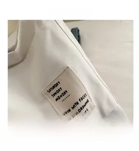 Close-up of beige canvas tote bag detail featuring creative embroidered text patches
