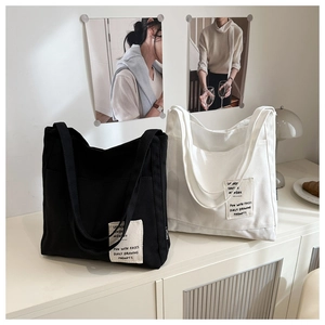 Detail of canvas tote bags with contrast text patch and side pocket on white side cabinet