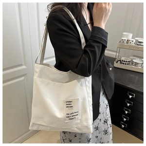 Close-up of a white canvas tote bag with artistic typography print for daily commute