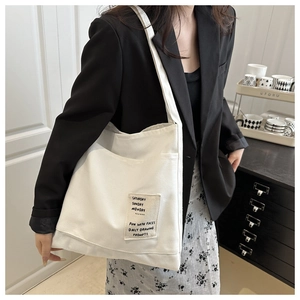 Detailed view of white canvas tote bag featuring a minimalist graphic rectangular patch