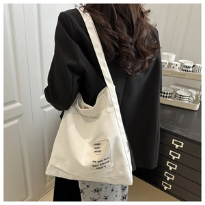 Detailed back view of a white canvas tote bag worn over the shoulder in a lifestyle setting