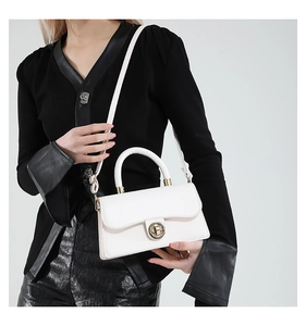 Close-up of elegant white leather handbag with golden metal clasp on female model