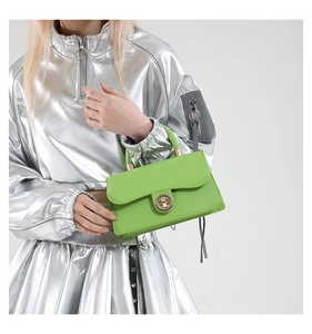 Macro shot of bright green retro square handbag with metallic twist lock and tassel detail