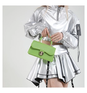 Close-up of bright green handbag with metal twist lock and minimalist leather texture