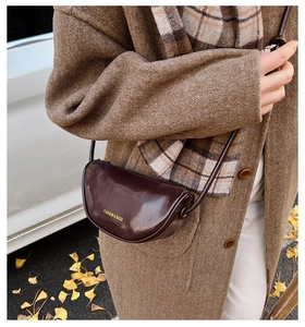 Close-up of retro brown crescent bag with gold Fashion & Bags lettering on wool coat