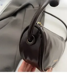 Detailed macro of glossy wine red leather texture and metallic zipper on round handbag