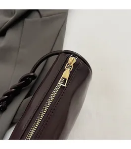 Detail of smooth golden metal zipper and dark reddish brown leather shoulder bag