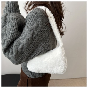 Close-up of white plush shoulder bag on model featuring soft faux fur texture and matching strap