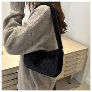 Close-up of black faux fur underarm bag with glossy texture and plush shoulder strap