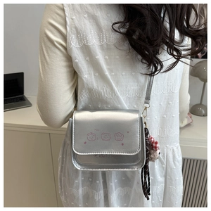 Silver metallic crossbody bag featuring a pink cartoon bear print and stylish accessories