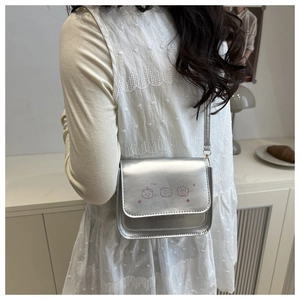 Detail of silver metallic square bag with pink cartoon prints and adjustable strap