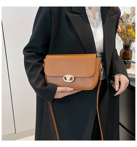 Détail du sac à bandoulière en cuir marron avec fermoir doré ovale et rabat chic