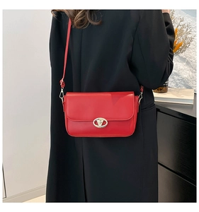 Détail d'un sac à bandoulière en cuir rouge porté sur un fond d'intérieur moderne