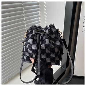 Detail of black and white tweed bucket bag featuring fringe texture and drawstring closure