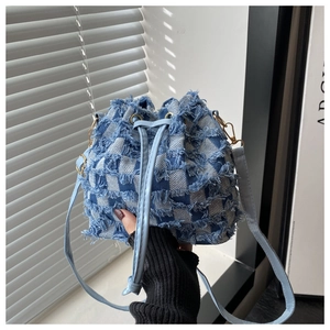 Blue denim checkerboard bucket bag detail featuring frayed edges and gold-tone hardware