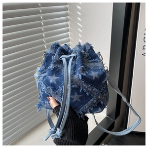 Detail of blue denim bucket bag featuring large white star print and raw frayed edges