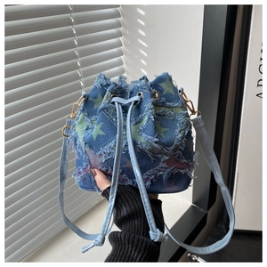 Detail of blue denim bucket bag with green star patterns and trendy frayed edges