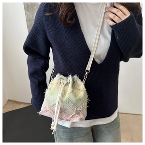 Detail of canvas drawstring bucket bag with star prints and frayed fringe edges