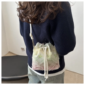 Detail of a rainbow canvas mini bucket bag featuring frayed edges and star patterns