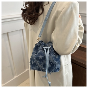 Détail du sac seau en denim bleu avec motifs étoiles effilochés et bandoulière