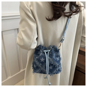 Détail du sac seau en denim avec motifs d'étoiles, bords effilés et cordon serrage
