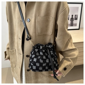 Detail of checkered tweed bucket bag with fringe trim on khaki workwear jacket