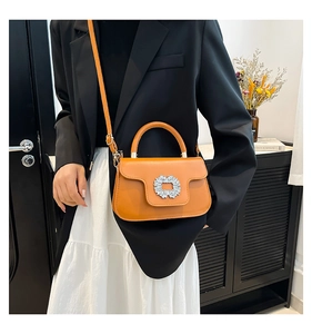 Detail of a bright orange leather handbag with a sparkling crystal round buckle